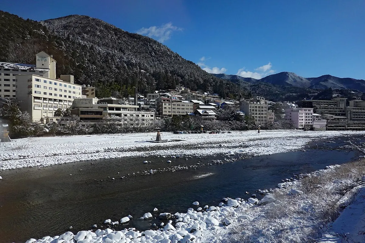 雪の積もった飛騨川の河原と、川沿いに並ぶ下呂温泉の旅館やホテル