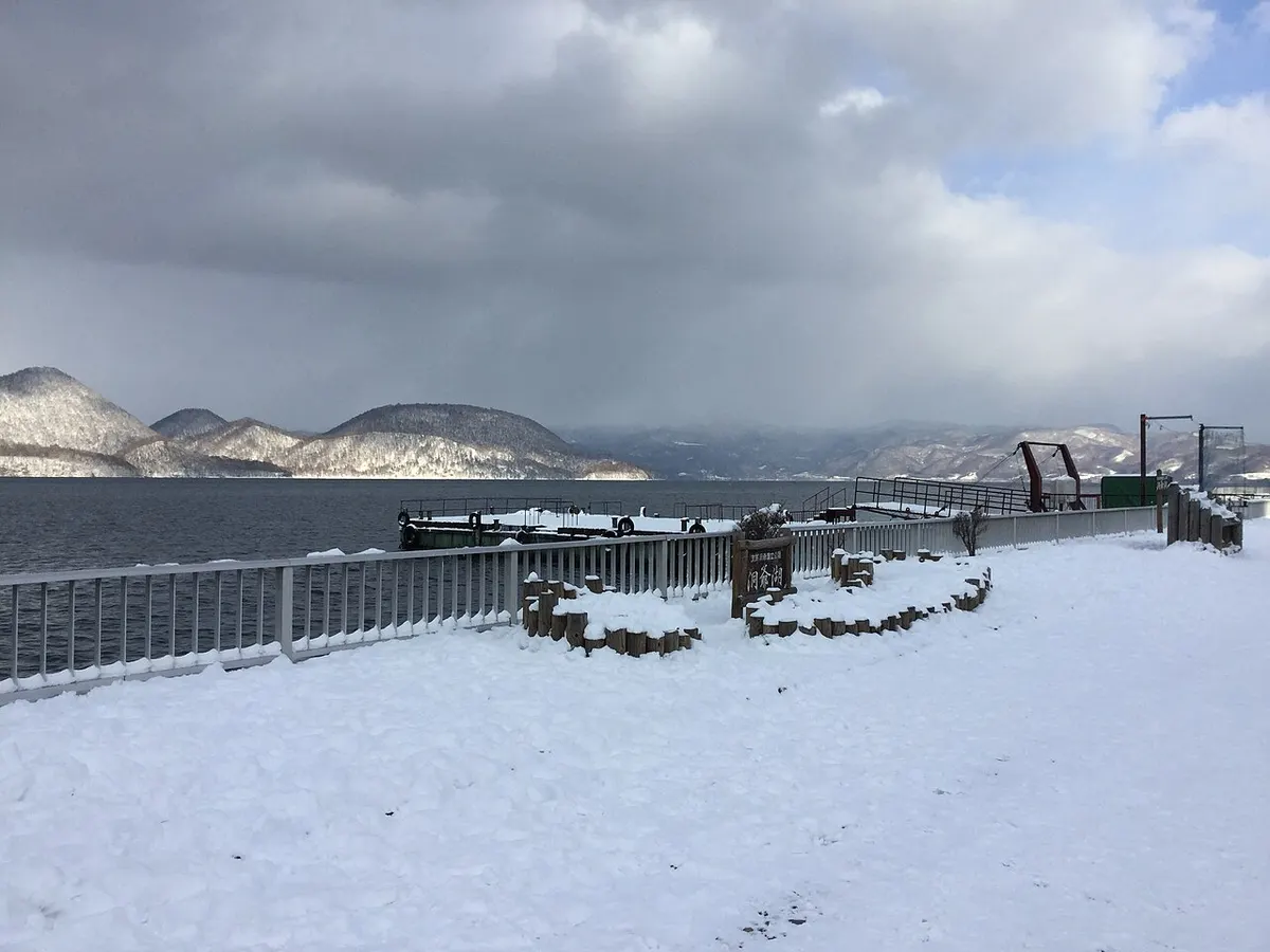 雪の積もった洞爺湖の湖畔と、雪をかぶった中島の山々