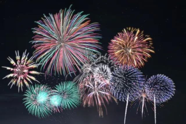 夜空に色とりどりの打ち上げ花火が重なって開く様子